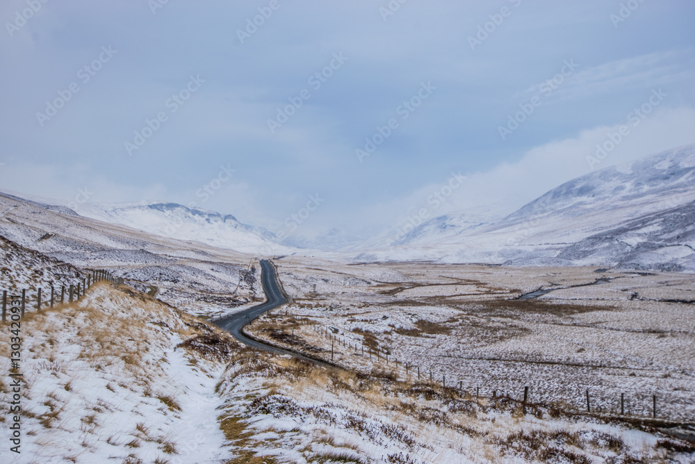 Obraz premium Winding road in a Snowy Scottish Mountain Valley