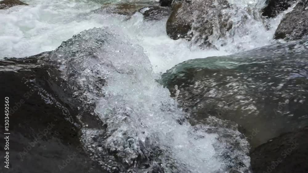 River water crashing on rock in slow motion, camera tracks forwards into the breaking white foam. In slow motion. River water crashing on rock in slow motion, camera tracks forwards into the breaking white foam. In slow motion.