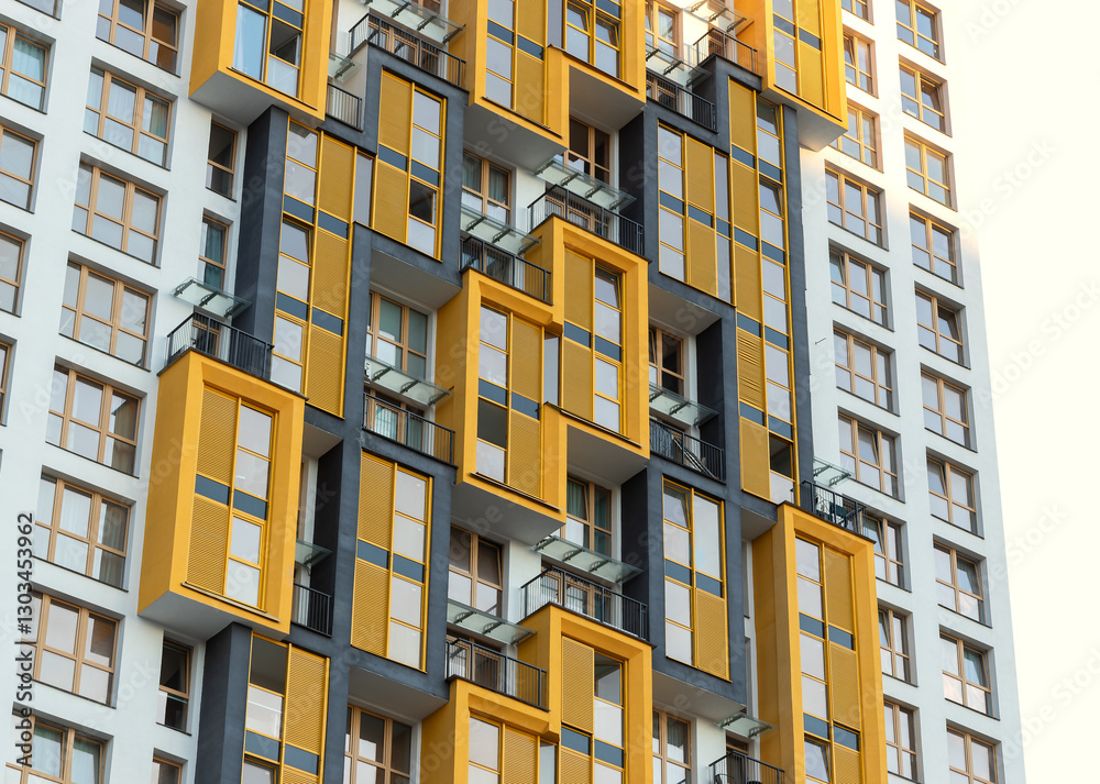 Fototapeta premium Modern high-rise residential building with bright yellow balconies in an urban metropolis.