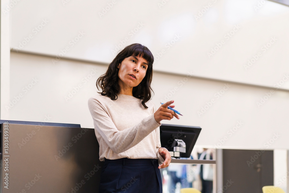 Confident female teacher explaining while pointing in lecture hall at university Confident female teacher explaining while pointing in lecture hall at university
