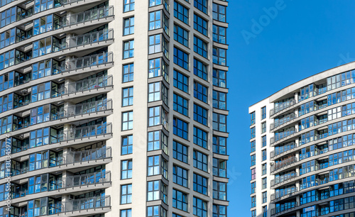 Tall modern building in urban neighborhood. New multi-story condominium under development, with large windows and contemporary design. Investment property, residential accommodation with views of the