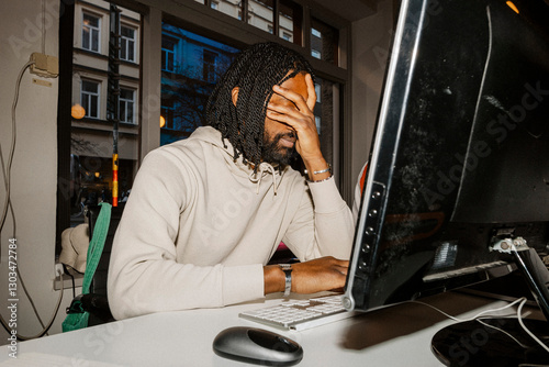 Sad male entrepreneur with head in hand while sitting at desk in office photo