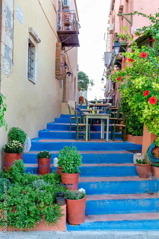 A bright blue staircase decorated with potted plants and a charming c charming restaurant awaits you in the quaint village. Greece. Rethymno.