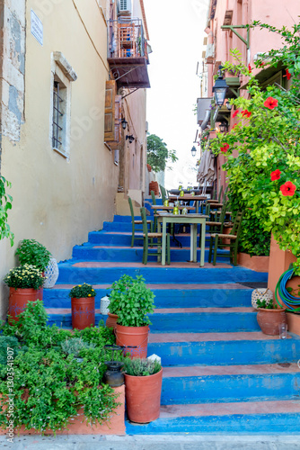 Obraz na płótnie A bright blue staircase decorated with potted plants and a charming c charming restaurant awaits you in the quaint village. Greece. Rethymno. w salonie