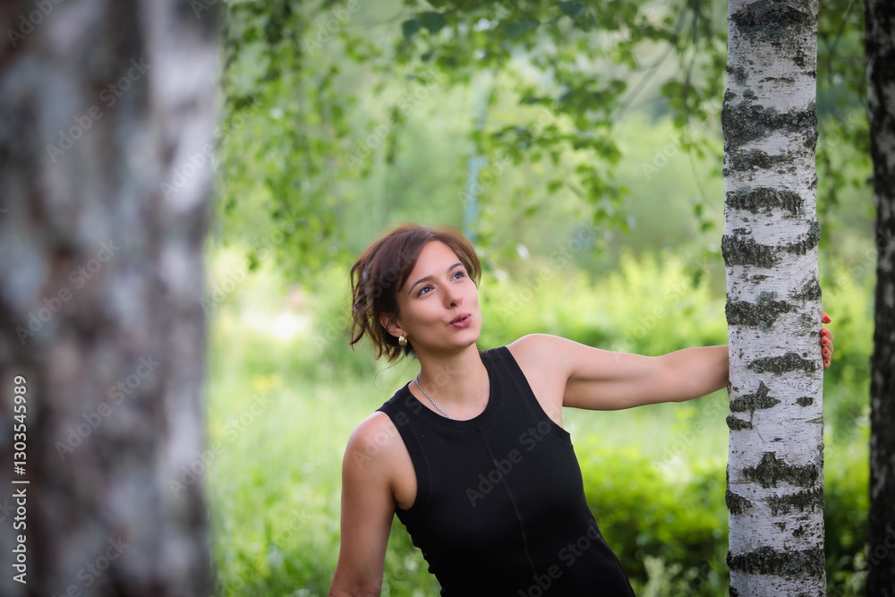 Emotional woman posing in park surrounded by birch trees Emotional woman posing in park surrounded by birch trees