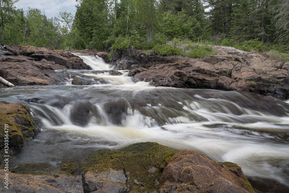 Long exposure of a river cascading through a green forest. Long exposure of a river cascading through a green forest.