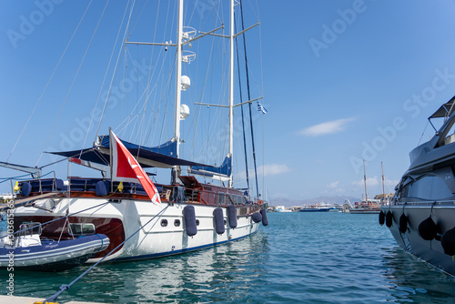 Luxury boats moored around harbour with large white ketch in foreground.