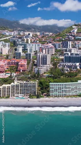 Aerial view of turquoise waters of Praia Formosa beach and colorful houses and hotels on hills in Funchal Madeira island Portugal