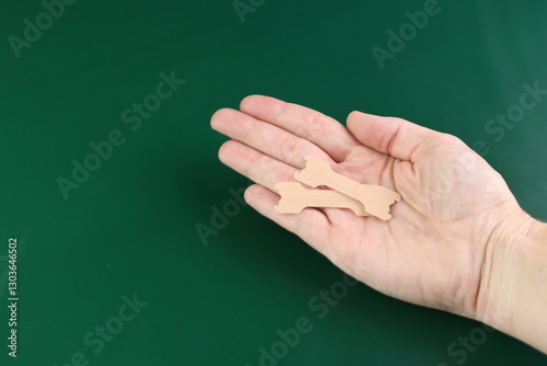 Woman holding in the hand a nasal strip with green background and copy space in the left side 