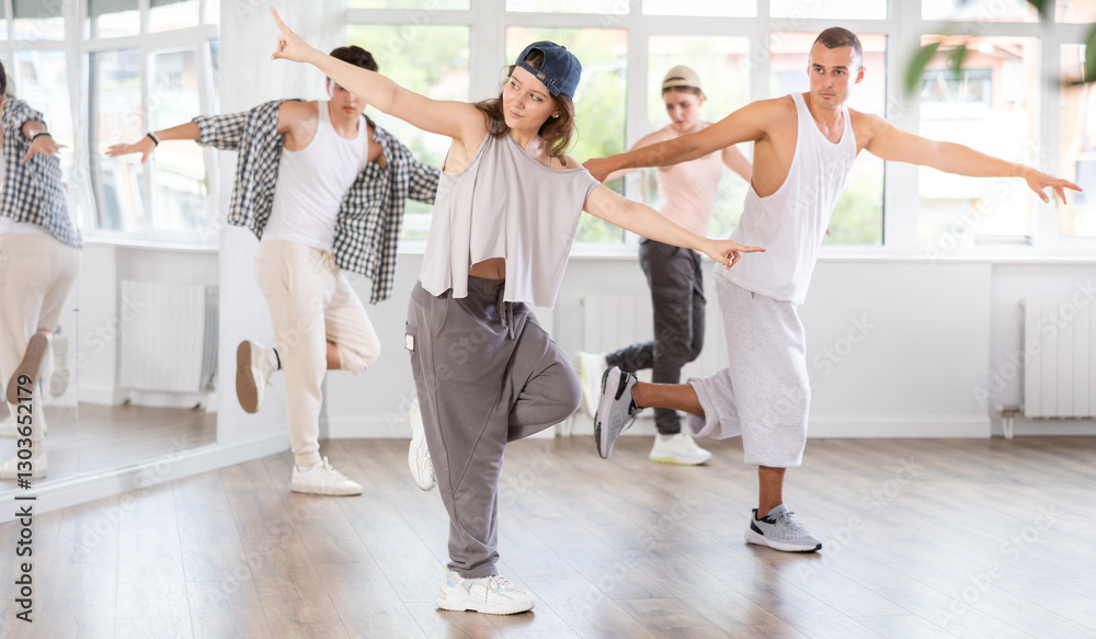 Obraz premium Dynamic young woman training hip hop kick steps in dancehall during workout session