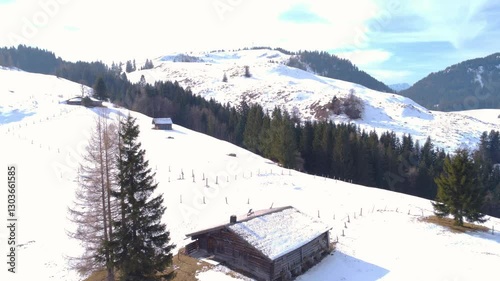 Mountain huts in the midst of winter silence: small wooden buildings lost among snow-covered slopes.