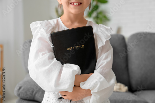 Fotografija Cute little girl with Bible at home, closeup