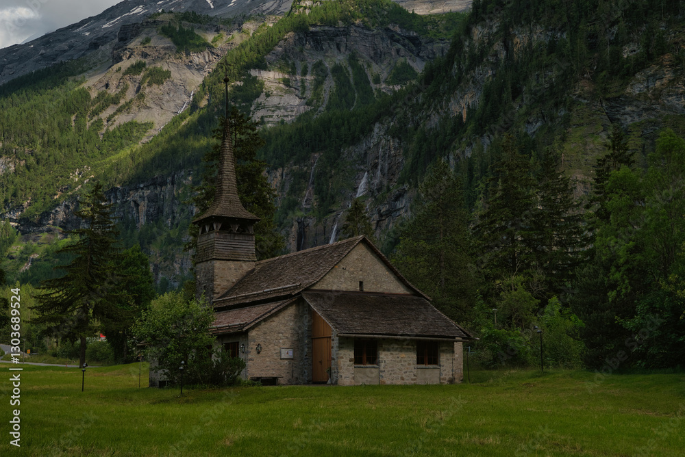 Landscape photograph of the Kandersteg Church in the middle of a field with mountains in the background, Canton Bern, Switzerland. Landscape photograph of the Kandersteg Church in the middle of a field with mountains in the background, Canton Bern, Switzerland.
