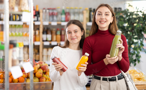 Glad teeny girl and mom trying to choose the best smoothie in grocery shop