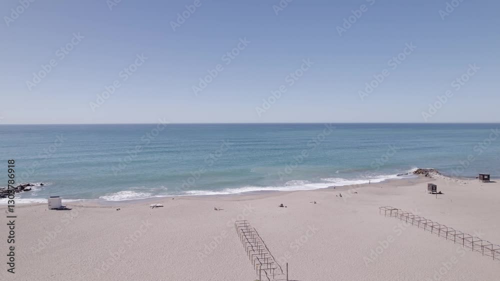 Vista aérea del mar con olas llegando, día soleado, cielo azul y agua cristalina desde un dron