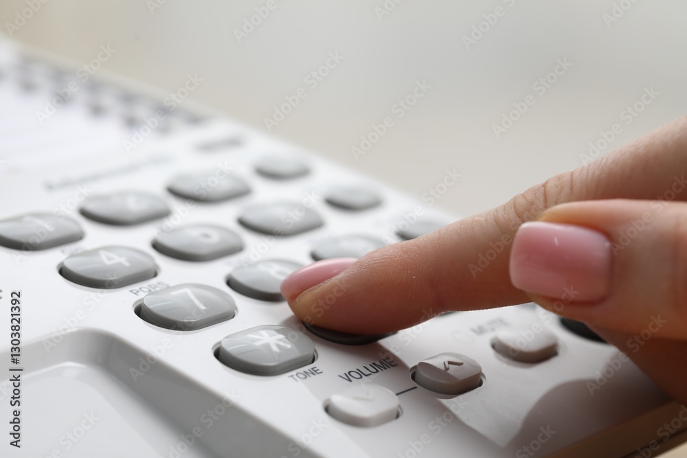 Woman dialing number on telephone against blurred grey background, closeup Woman dialing number on telephone against blurred grey background, closeup