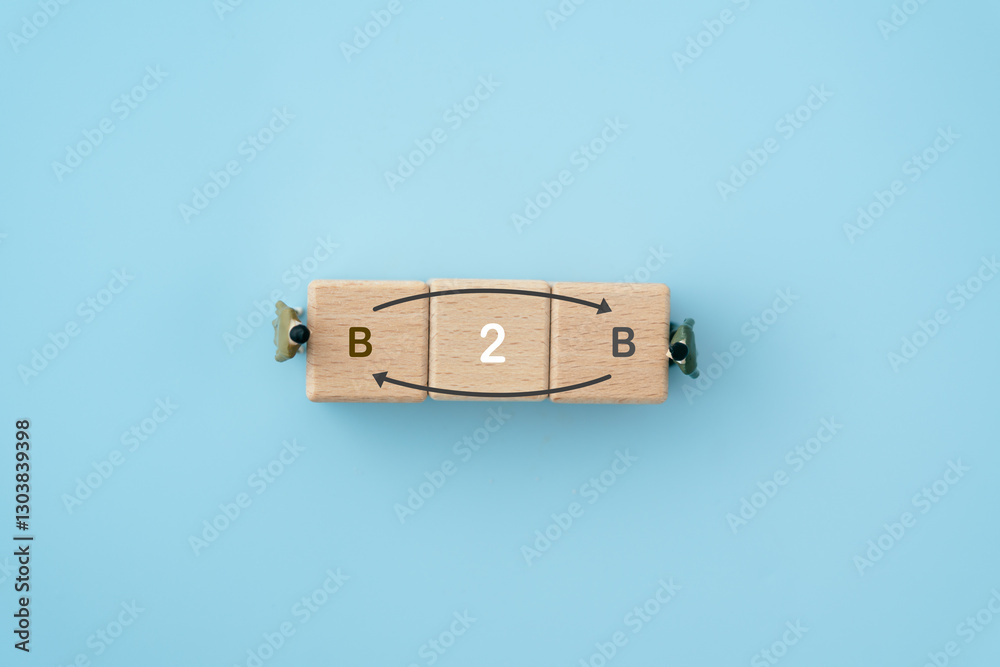 Fototapeta premium Business concept success process. wooden cube blocks with b2b text and top view of miniature businessman on blue background, including copy space