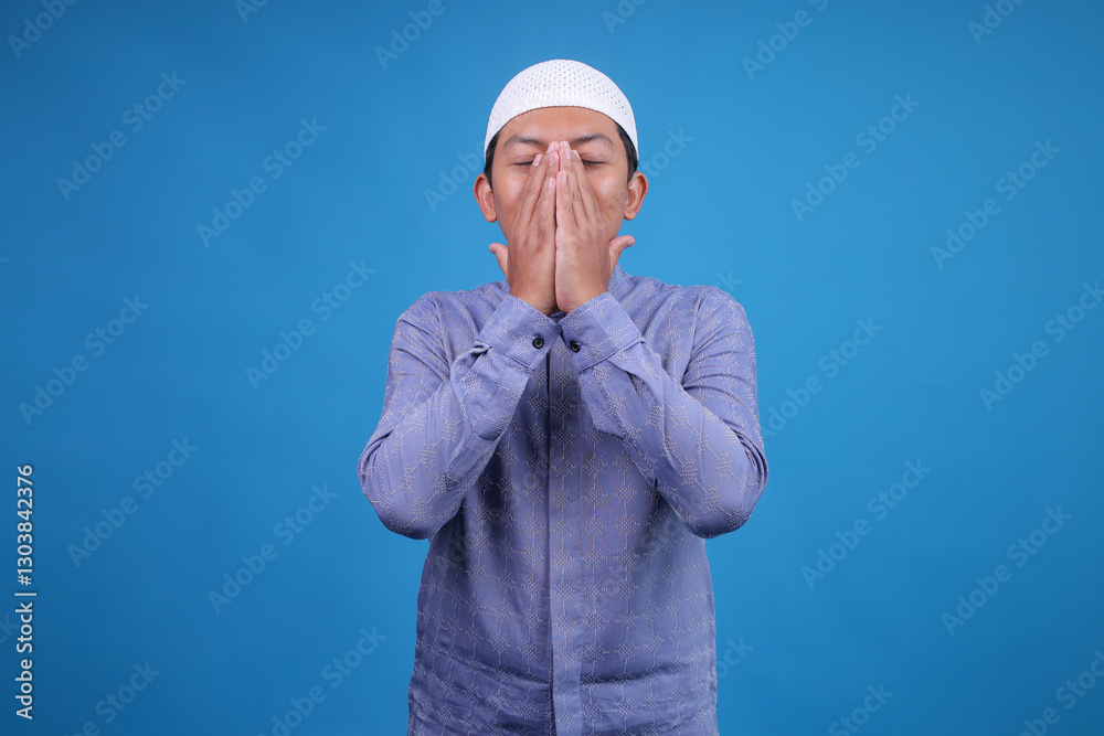 Portrait Of Muslim Man Wiping Face After Praying On Blue Background Portrait Of Muslim Man Wiping Face After Praying On Blue Background