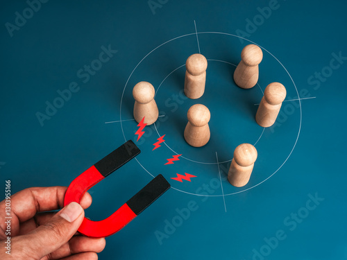 Business digital marketing, target audience, attract leads and customers concept. Wood human people attracted by magnet in hand on blue background. Business team building, recruitment, hiring concept.