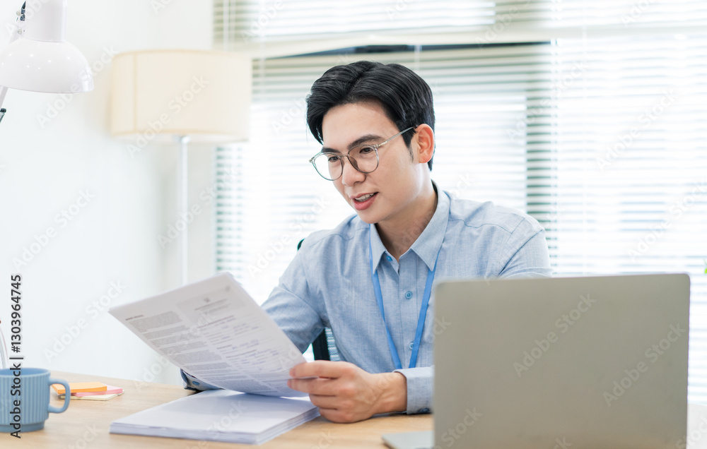 Young professional engaged in work while reviewing documents in a modern office setting during daytime Young professional engaged in work while reviewing documents in a modern office setting during daytime