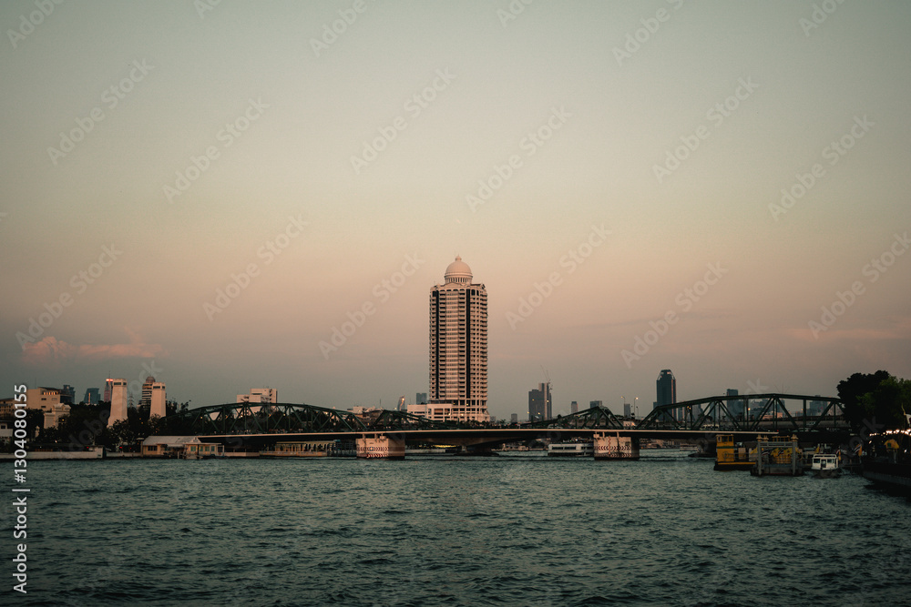 Fototapeta premium A scenic view of the Phra Phutthayotfa Bridge spanning the Chao Phraya River in Bangkok, captured from the River Walk near Wat Kanlayanamit Woramahawihan. The bridge.