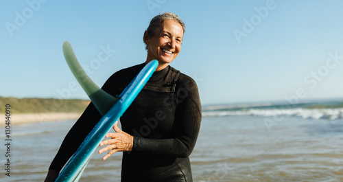Photography Mature woman with a single fin surfboard at the beach