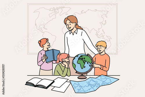 Geography teacher teaches small children using maps and globes or atlases, standing in classroom. Happy schoolchildren rejoice with interest learning new facts during geography lesson