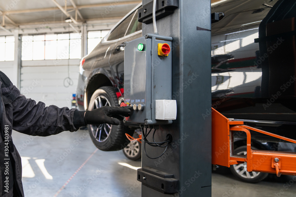 Fototapeta premium Serviceman checks car suspension on a column lift in car service.