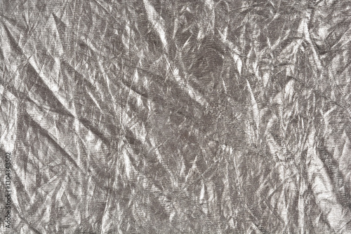 A close-up shot of crumpled silver fabric, showcasing its reflective surface and intricate texture