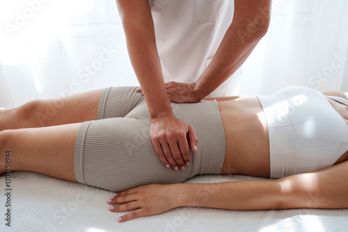 Osteopath massaging teenage patient's pelvis in treatment room