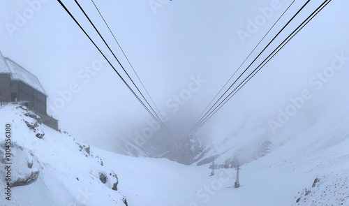 Empty cables of a cable car in the high mountains. Around a landscape with snow, ice and fog.