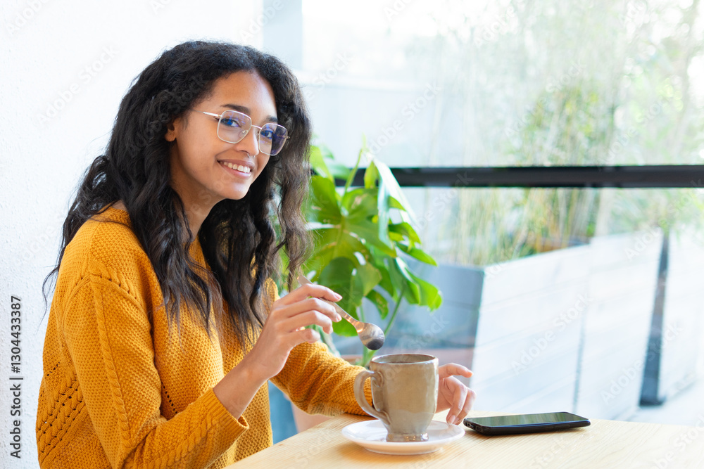 Latin woman relaxing with coffee and smartphone in cafe