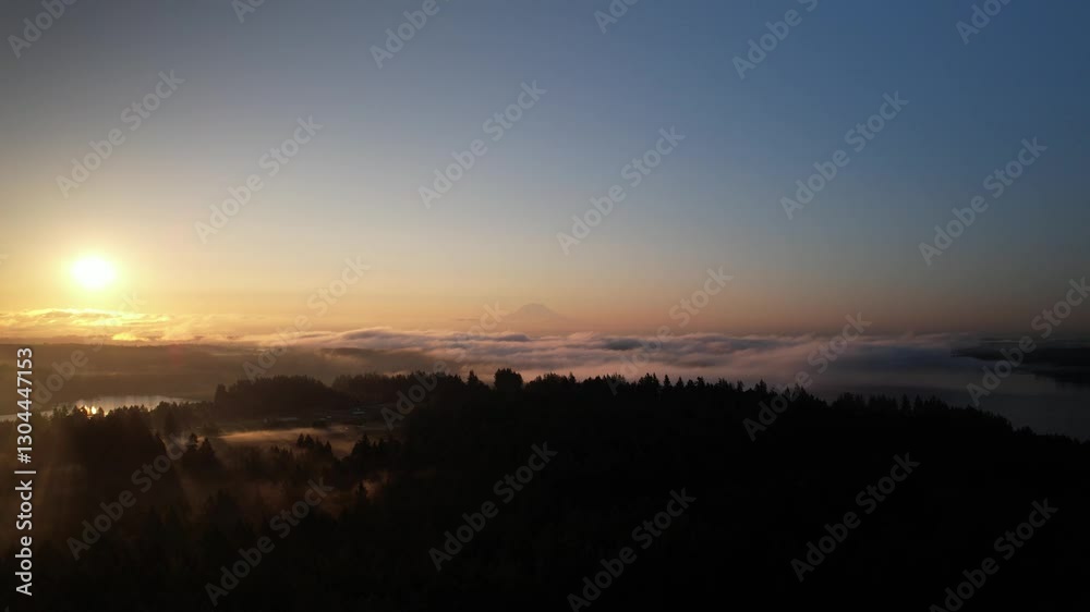 Push in drone shot of foggy sunrise over Mount Rainier (Tahoma) with forest and skyscape in Cascade Range, Mount Rainier National Park, west-central Washington state, USA Push in drone shot of foggy sunrise over Mount Rainier (Tahoma) with forest and skyscape in Cascade Range, Mount Rainier National Park, west-central Washington state, USA