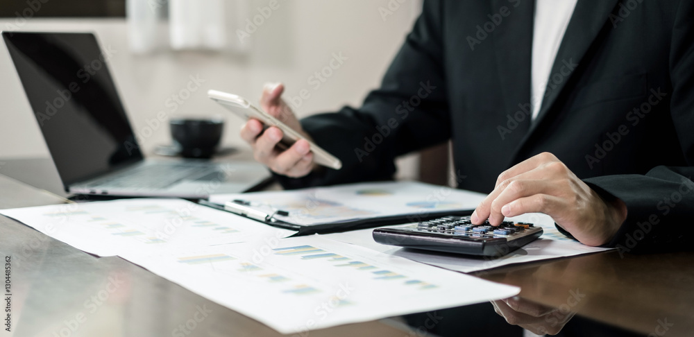 Fototapeta premium The businessman hand sits at their desks and calculates financial graphs showing the results of their investments planning the process of successful business growth