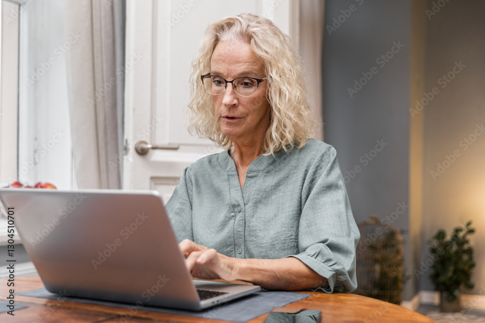 Senior elegant woman sits at table typing on keyboard. Cheerful aged woman working remotely using laptop. Older focused businesswoman browsing online. Female elegant writer enjoying creative process Senior elegant woman sits at table typing on keyboard. Cheerful aged woman working remotely using laptop. Older focused businesswoman browsing online. Female elegant writer enjoying creative process