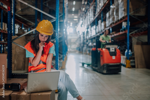 Female warehouse worker using laptop and thinking about logistics