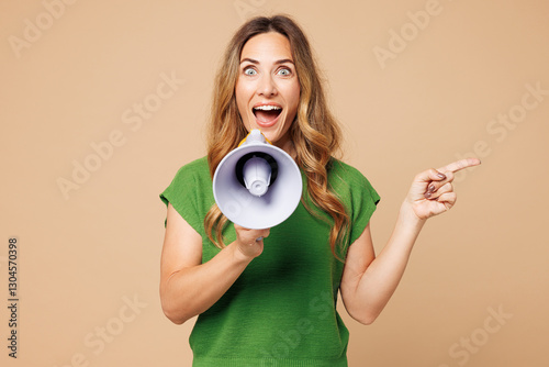 Young woman wearing green t-shirt casual clothes hold in hand megaphone scream announces discounts sale Hurry up point finger aside isolated on plain pastel light beige background. Lifestyle concept.