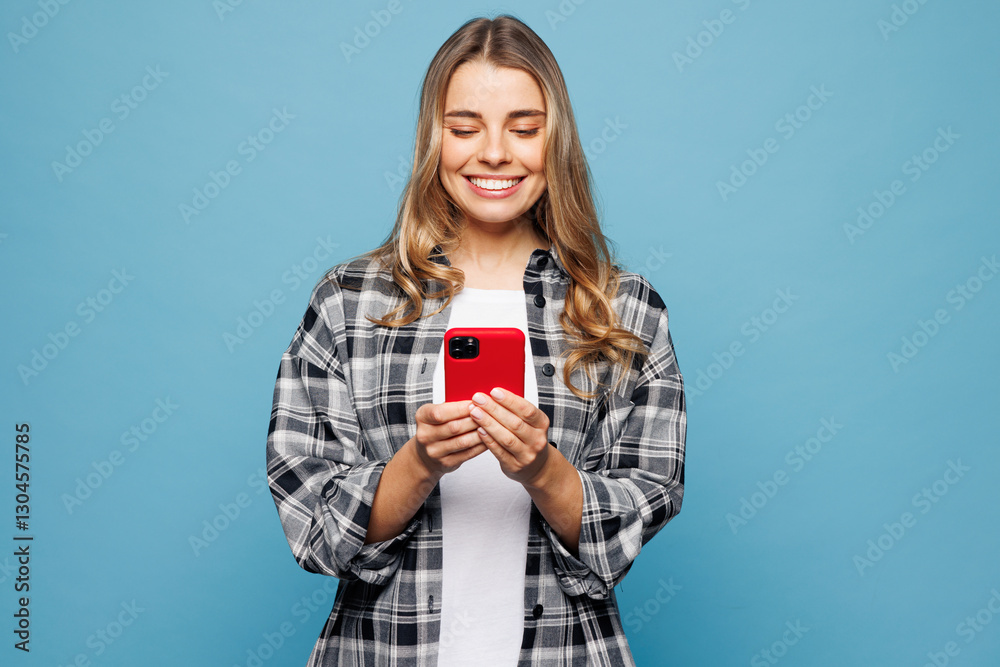 Young smiling woman she wears checkered grey shirt casual clothes hold in hand use mobile cell phone chat online isolated on plain pastel light blue cyan background studio portrait. Lifestyle concept. Young smiling woman she wears checkered grey shirt casual clothes hold in hand use mobile cell phone chat online isolated on plain pastel light blue cyan background studio portrait. Lifestyle concept.