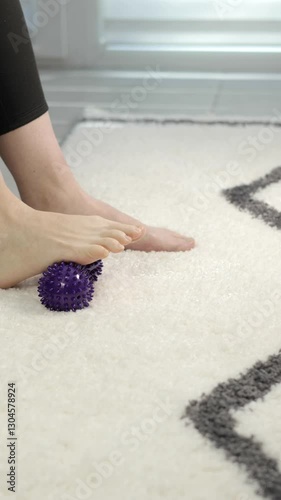 Vertical video, Woman is training with foot massage ball from muscle pain and stress. Relaxation massage after hard work day. 4k footage.