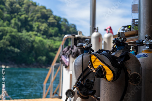 Diving equipment on a liveaboard with an Island in the Background. A mask is hanging on a airtank 