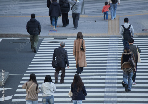 冬の都市の街の交差点の横断歩道を渡る人々の姿 photo