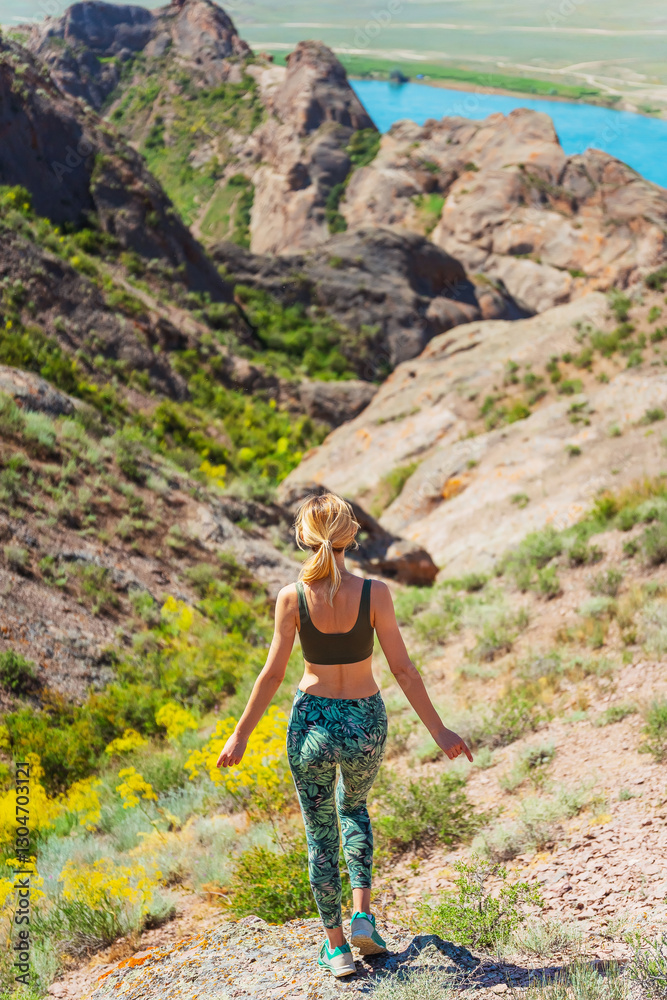 Naklejka premium girl stands on a rock against the backdrop of the steppe. woman takes a break from running