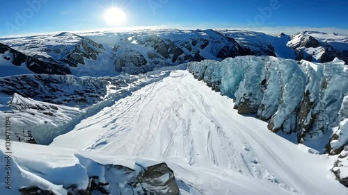 Aerial view flying over picturesque mountain ridge snowy rock texture sun light blue sky landscape. FPV sports drone empty alpine scenery winter glacier freeze valley natural cliff range freeze summit