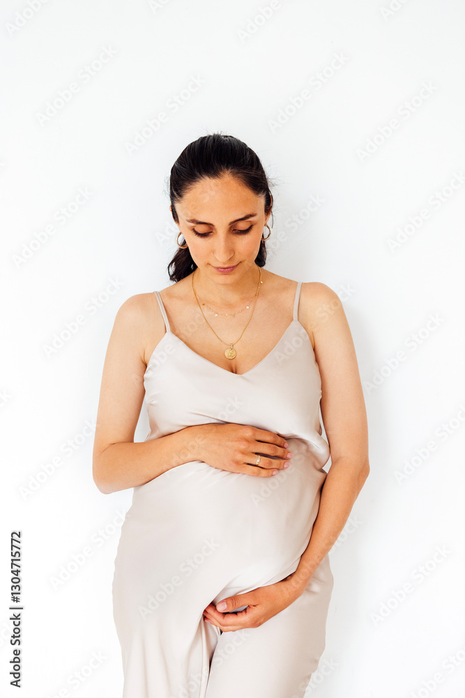 A young pregnant woman stands and gently holds her belly. White isolated background A young pregnant woman stands and gently holds her belly. White isolated background