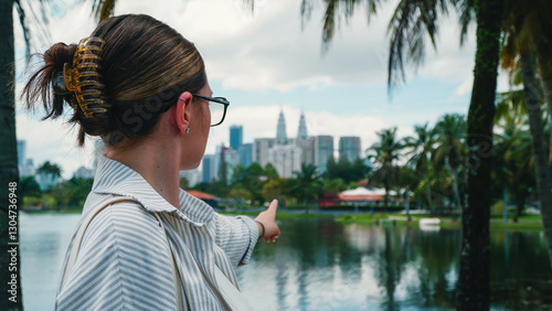 Photography Young traveller girl looking at the iconic Petronas Towers from the nearby KLCC
