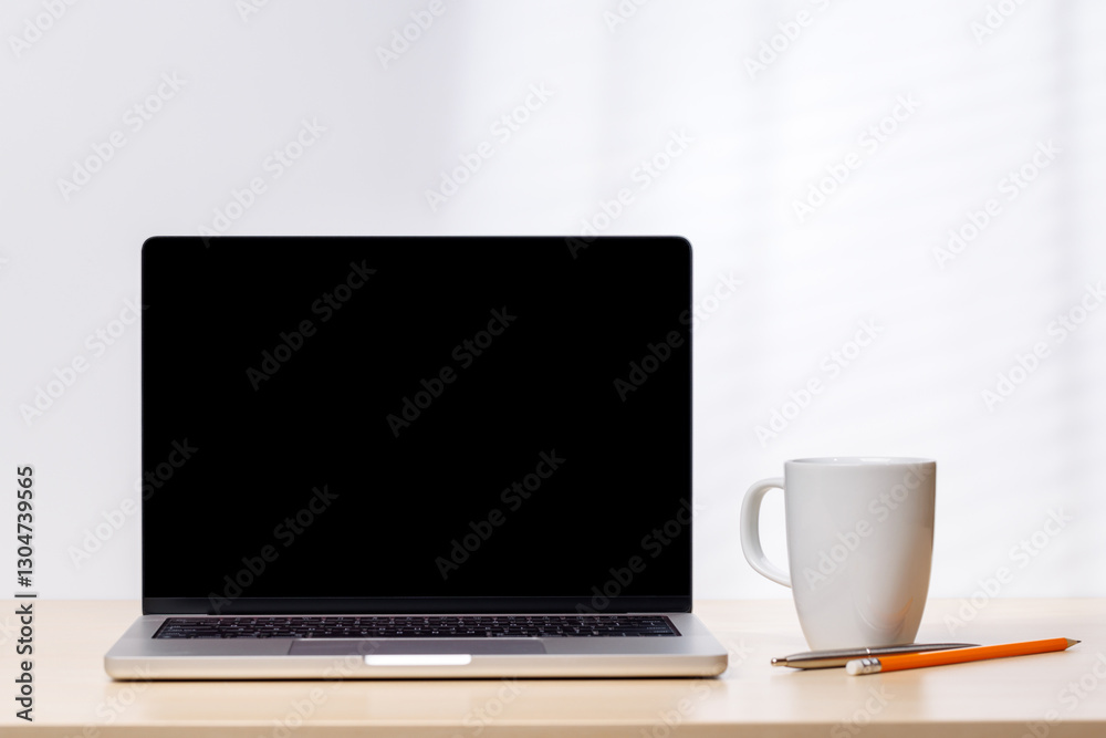 A laptop with a blank screen surrounded by office supplies A laptop with a blank screen surrounded by office supplies