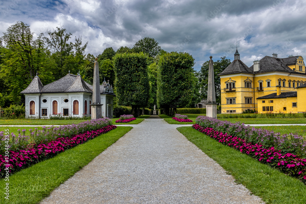 Obraz premium Weg führt durch den Park auf die Gebäude vom Schloss Hellbrunn in Salzburg