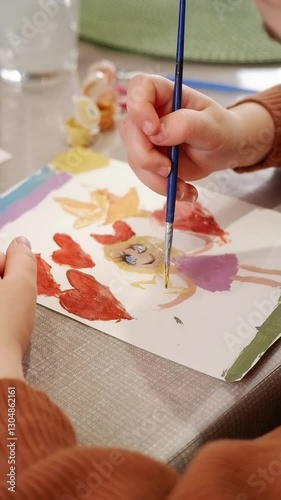 Kid painting red hearts and a girl with a yellow dress on white paper