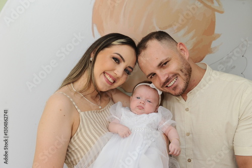 pai e mãe com bebe fofo no batizado  photo