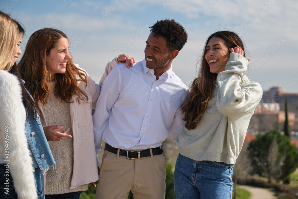 Four cheerful young students enjoying time together in a park, embracing and laughing Four cheerful young students enjoying time together in a park, embracing and laughing